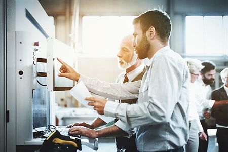 Technischer Fachwirt zeigt seinem Kollegen ein neues System am Monitor.