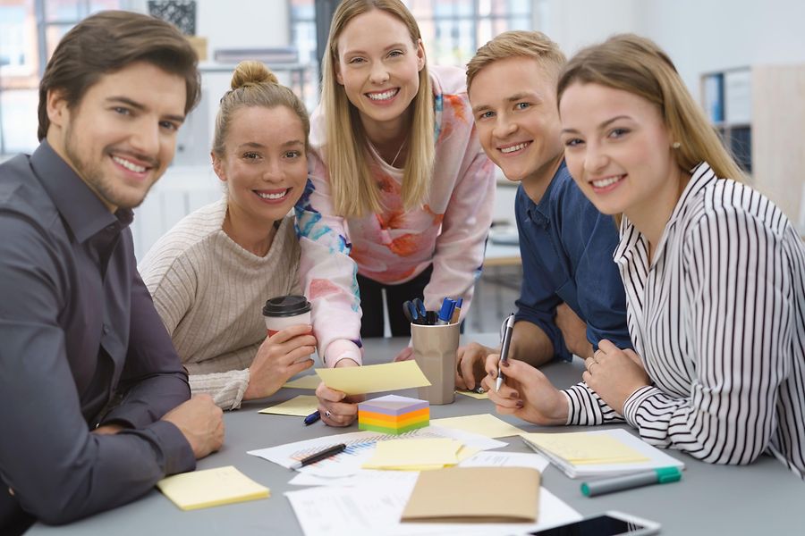 Das Foto zeigt eine Gruppe von Azubis an einem Tisch, die an einem Projekt arbeiten